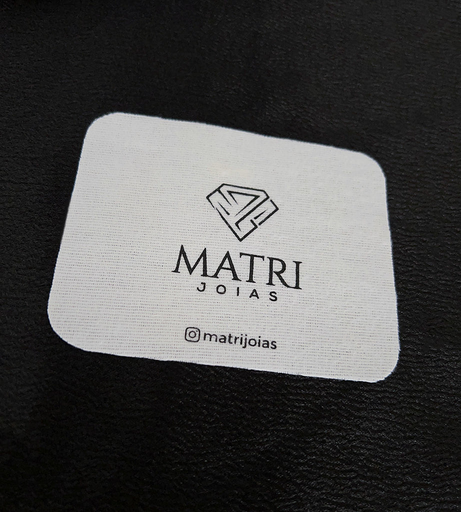 Flanela branca da Matri Joias com o logo da marca, sobre fundo preto
