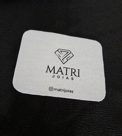 Flanela branca da Matri Joias com o logo da marca, sobre fundo preto